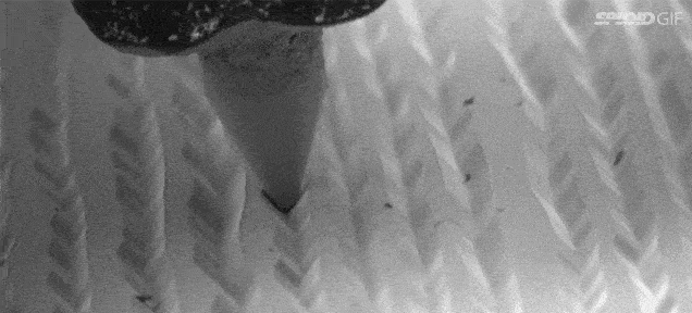 A close up gif of a record needle moving through a groove in a record
